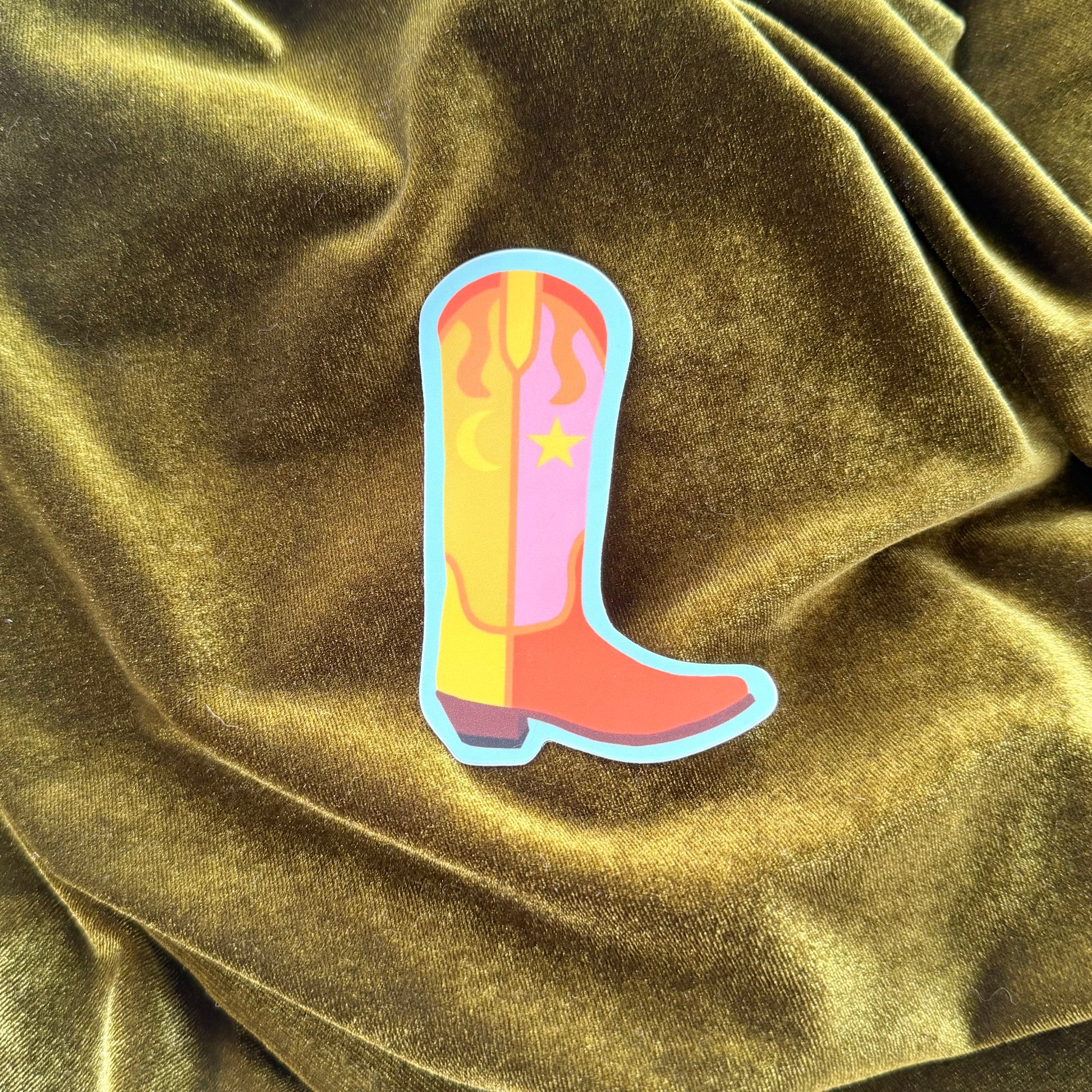Colorful cowboy boot sticker on a textured green fabric background